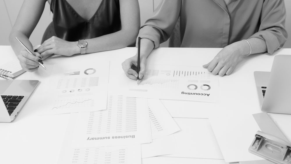 Dois profissionais analisando relatórios financeiros no escritório